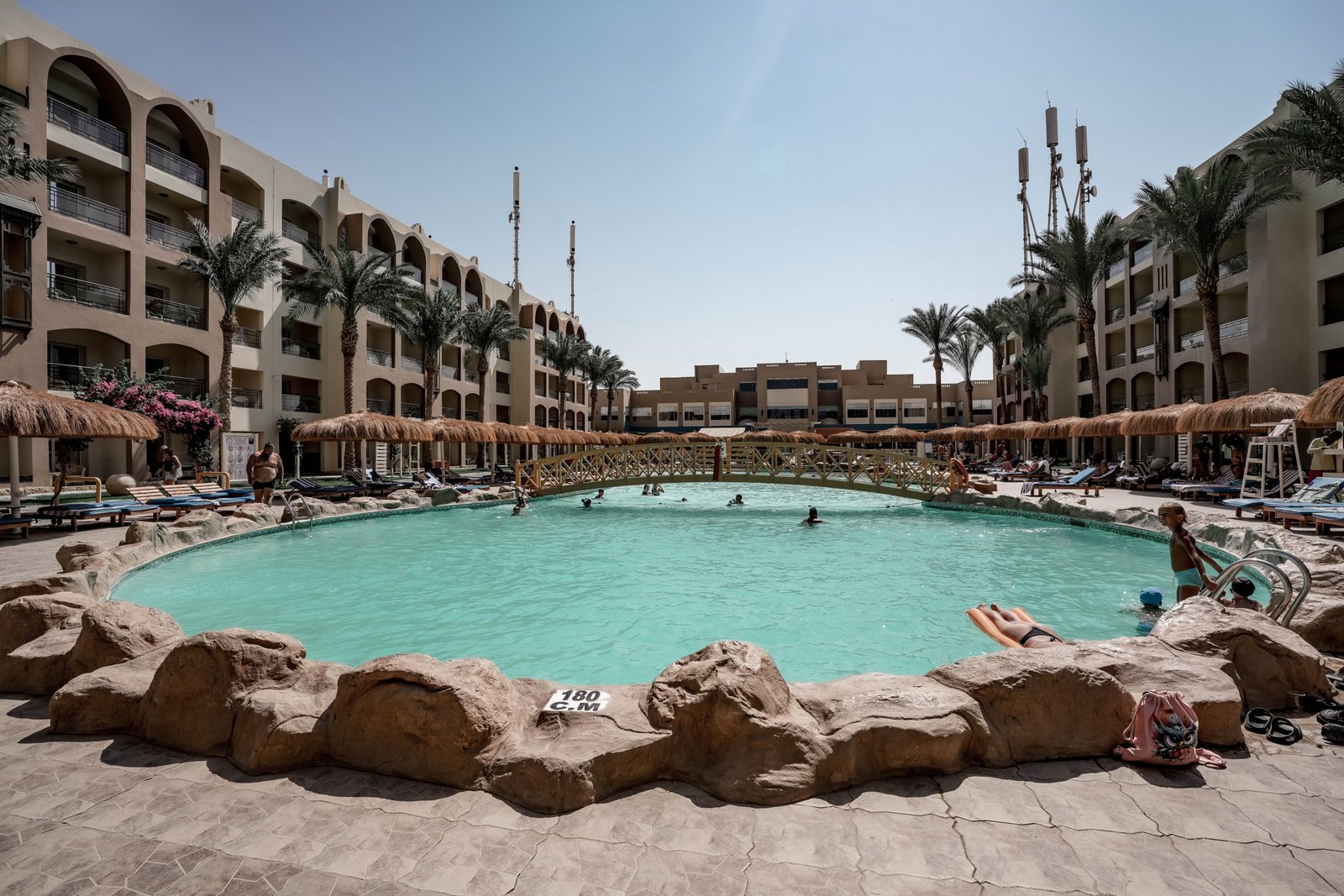 Luxury swimming pool at AlKarma Aqua Beach surrounded by palm trees and modern resort-style architecture.