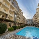 1 Bedroom apartment for sale in Florenza Khamsin Hurghada Luxury swimming pool at Florenza Khamsin surrounded by palm trees and elegant resort-style architecture.