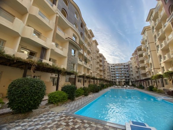 1 Bedroom apartment for sale in Florenza Khamsin Hurghada Luxury swimming pool at Florenza Khamsin surrounded by palm trees and elegant resort-style architecture.