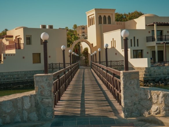 Aerial view of a lush green 18-hole championship golf course layout winding between turquoise water lagoons and premium luxury villas in El Gouna.
