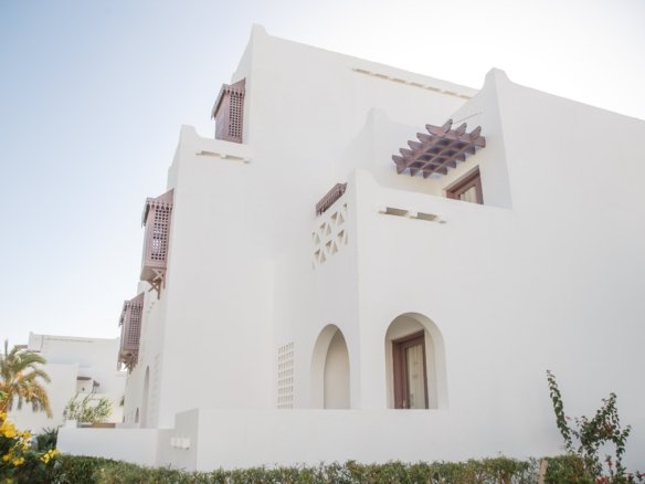 Scenic view of luxury yachts docked at Abu Tig Marina in El Gouna, showcasing premium waterfront apartments with classic Mediterranean-style architecture and outdoor dining spaces along the promenade.